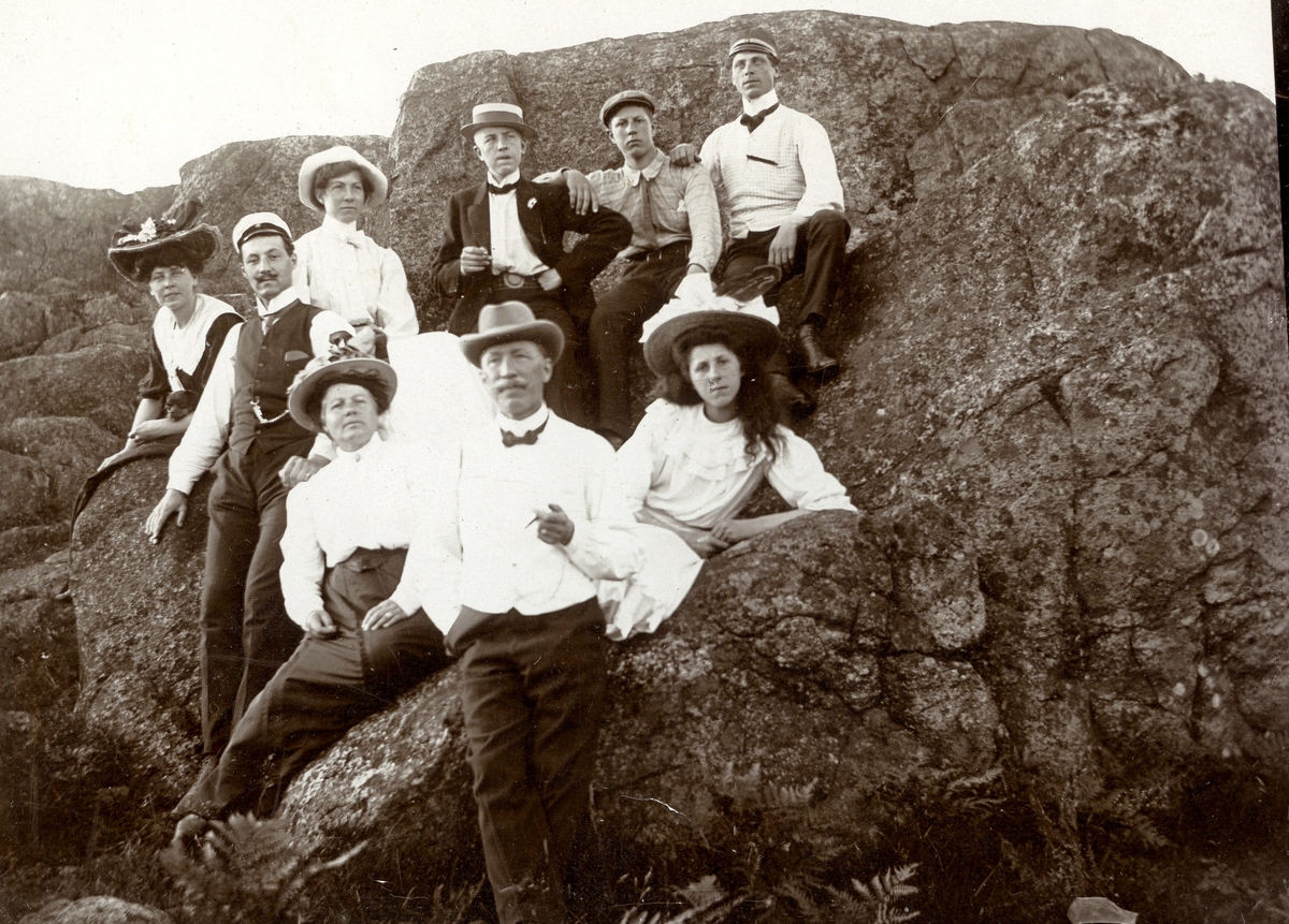 Uppklädda sommargäster från Göteborg som hyrde vid Livered 1:15 "Majas" cirka 1910. Personerna (namnuppgifter saknas) sitter på olika ställen på en bergsknalle.