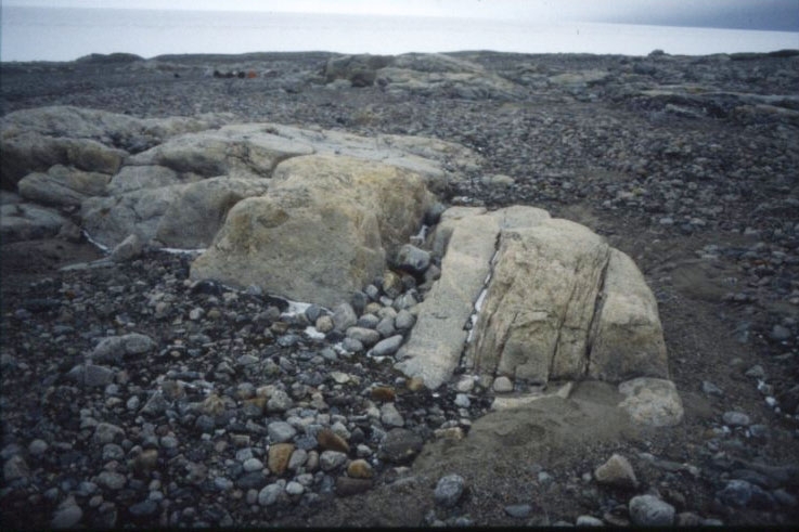 En stenig terräng och en smal skreva mellan två större stenar. Platsen där Nils Strindbergs återfanns 1930. Fyndplatsen för Andréexpeditionen.