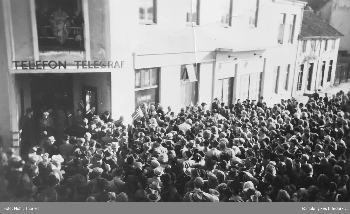 Frigjøringsdagene i Halden i mai 1945, etter andre verdenskrig. Folkemengde utenfor telegrafen. Grensepolitiets (Grepo) kontorer i Telegrafbygningen  blir besatt 9. mai av en milorggruppe.