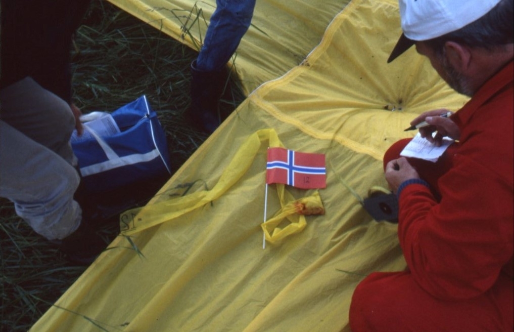Bild på ett gult ballonghölje. En liten norsk flagga ligger på höljet.