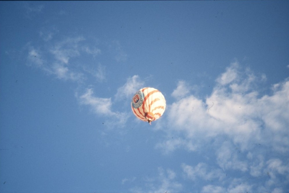 En röd- och vitrandig luftballongot en blå himmel. Bilden tagen från marken.