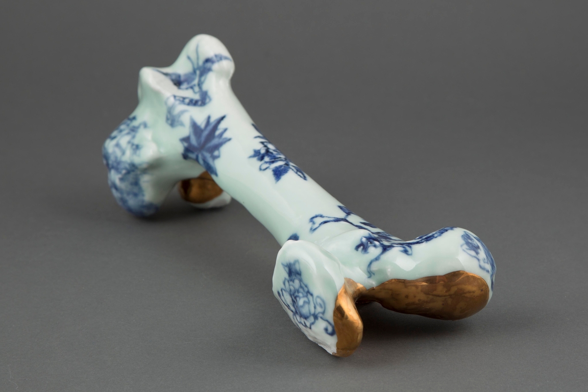 Et ben i porselen med sjømannstattoeringer i blå underglasur og bladgull.