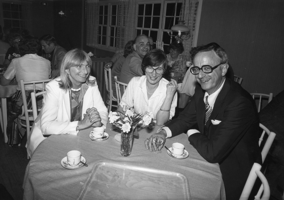 Inomhusbild från Folkets Park i Linköping, 1970-tal. Två kvinnor och en man runt ett runt bord, kaffekoppar och avec på bordet.