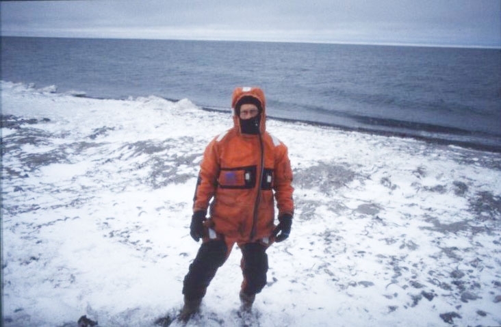 Porträtt av en man i överlevnadsdräkt på Vitöns snötäckta strand.