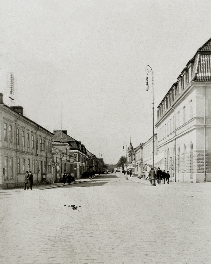 Storgatan, Växjö, 1915, västerut. Till vänster ser man några av husen i kvarteret Unaman (P.N. Perssons hörna och 
"Lindgren & Brandts" affär), till höger det nybyggda bankhuset (Skånska banken) i kvarteret Sunaman 3.