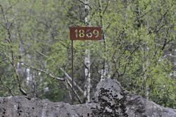 Metallskilt på stang med årstallet 1869 ved Fylkesveg 405