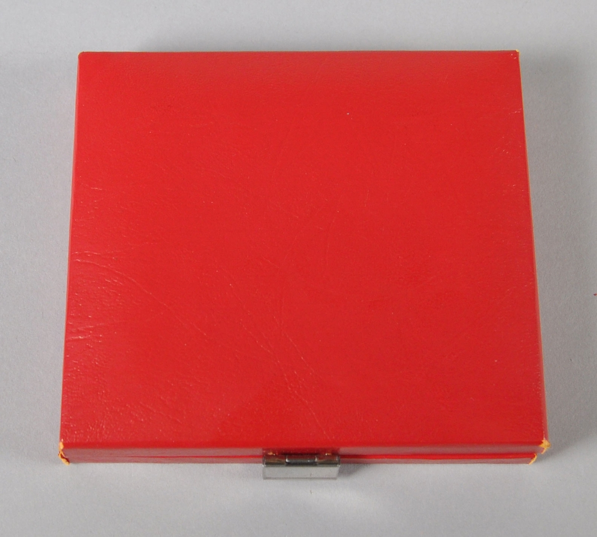 Merke (eller plakett) av metall med to hvite striper og en stjerne på rødt felt. Ligger i et rødt etui med rødt fløyelsfôr.