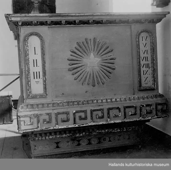 Predikstol av trä. Ljusgrå med förgyllda ornament. År 1816