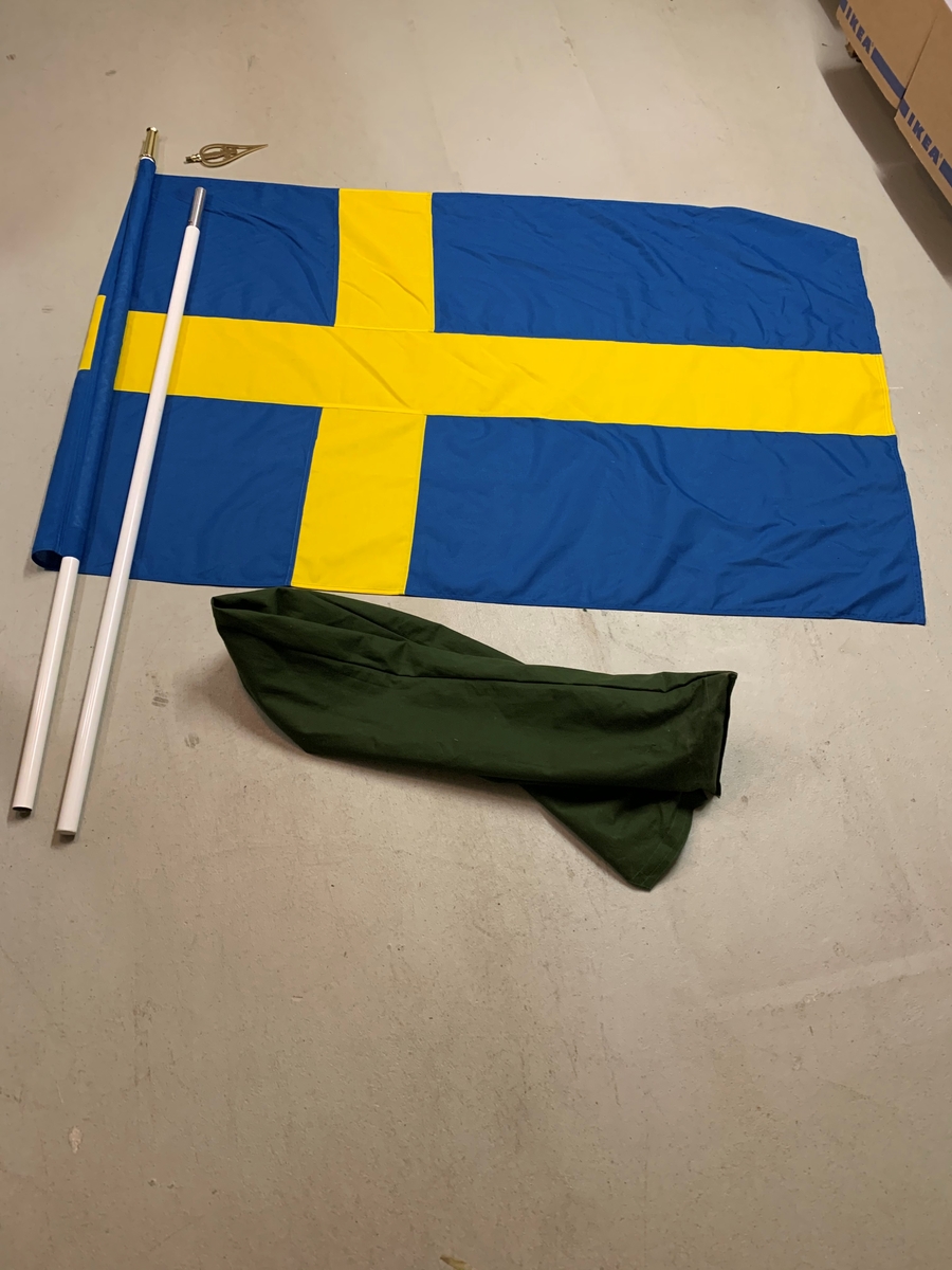 Svensk flagga i grönt flaggfodral. Stången är delbar
