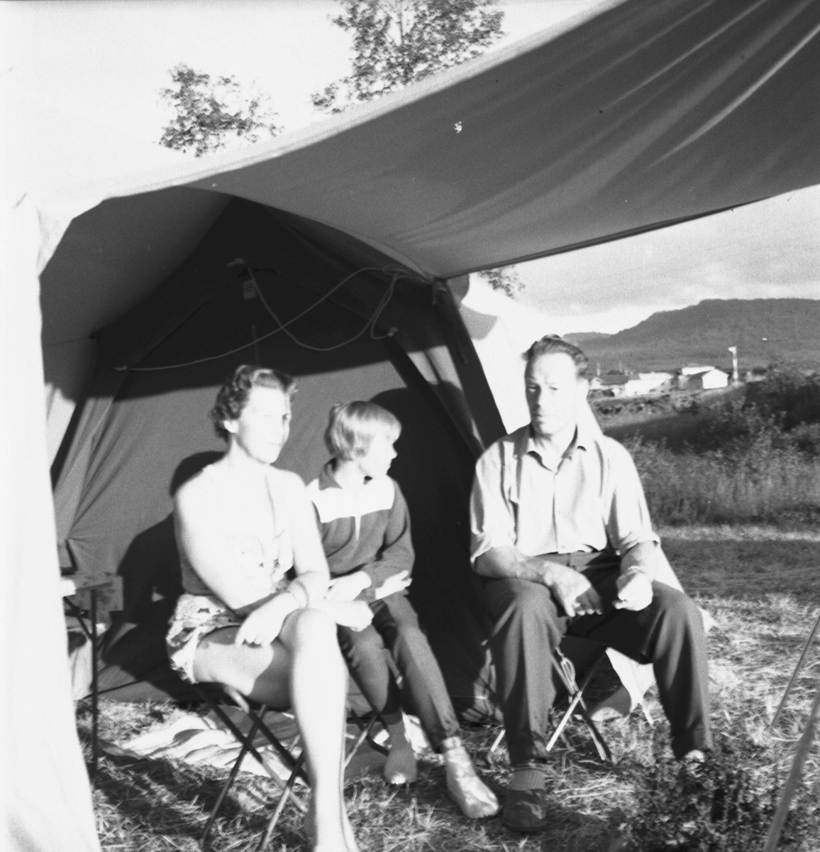Familie sitter i en teltåpning