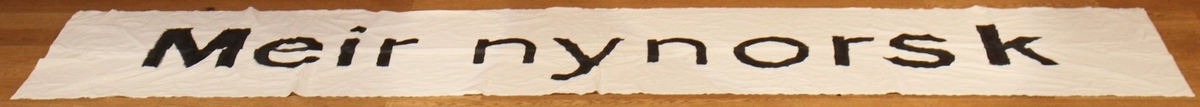 Banner frå arkivet til Norsk Målungdom. På banneret står teksten: "Meir nynorsk". Det er truleg at banneret har vore i bruk under ein aksjon for Norsk Målungdom.