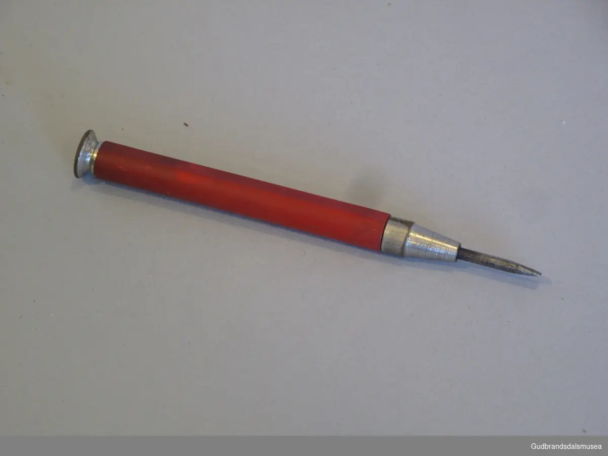 Skrujern brukt på Balopticon Model C. Produsert i USA fra rundt 1910 av Bausch & Lomb. Har form som en liten blyant med rødt palsskaft.