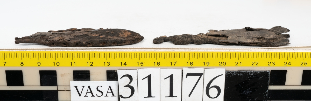 Delar från skobotten.
En sula, fyndnummer 31176. Längs med ytterkanten löper hål efter stygn med kvarsittande tråd. På sulans ovansida, narvsida, finns avtryck efter bindtråden. Vid hälpartiet finns hål efter träpligg.
En del av en klack, fyndnummer 31176:1. Klacken består av fem klacklappar varav en ligger löst ovanpå de andra. På undersidan finns kvarsittande träpligg. Klacken är snedsliten.
Ett bakre parti och ett främre parti av en sula. Den bakre delen av sulan, fyndnummer 31176:2, har en ritsad skåra som löper från hälen och fram mot partiet för hålfoten. Längs med ytterkanterna löper hål efter träpligg och stygn. I sulans hälparti finns kvarsittande träpligg. Ytterkanterna är delvist fragmentariska.