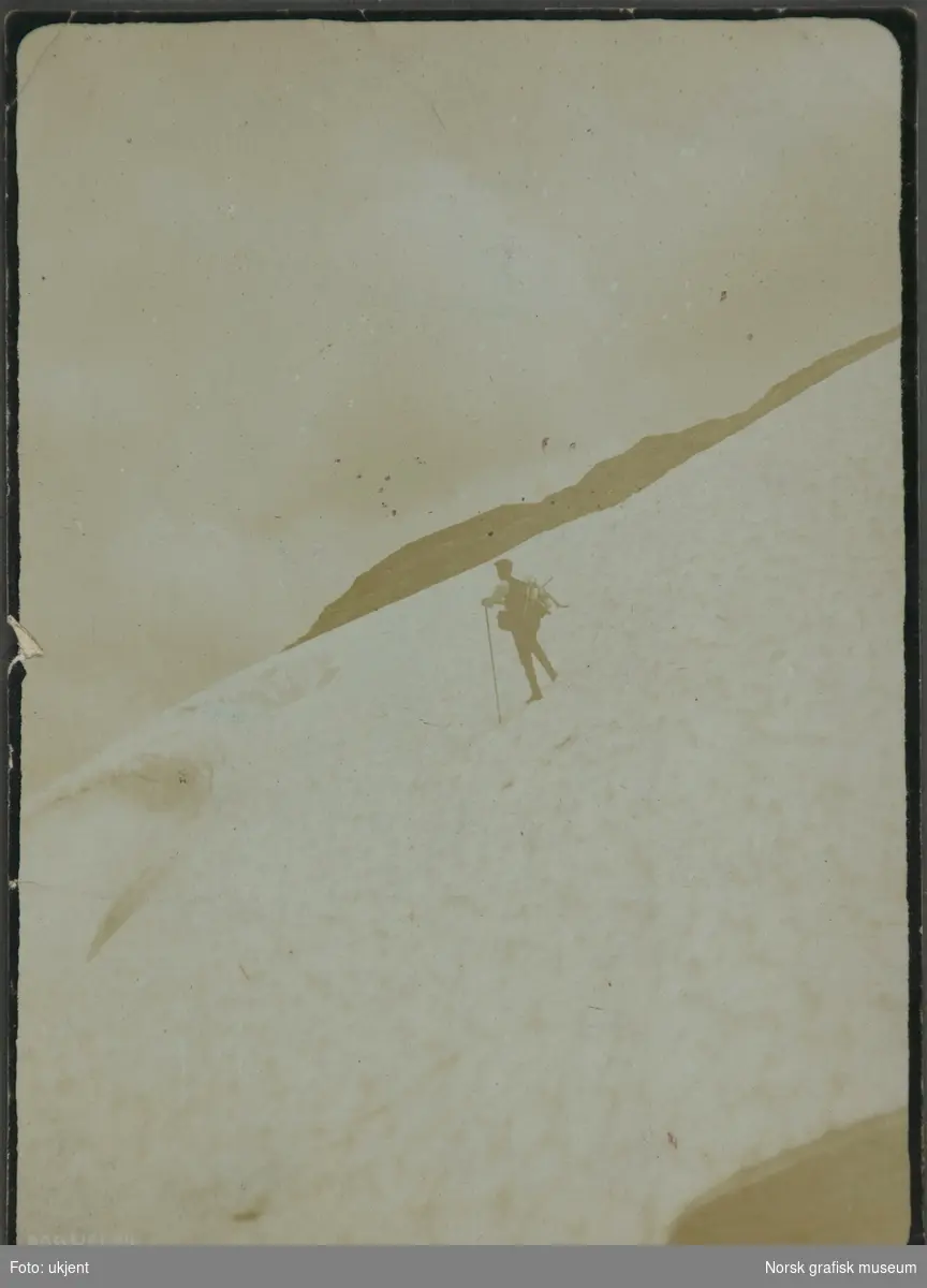 En mann på en snøfonn i fjellet.