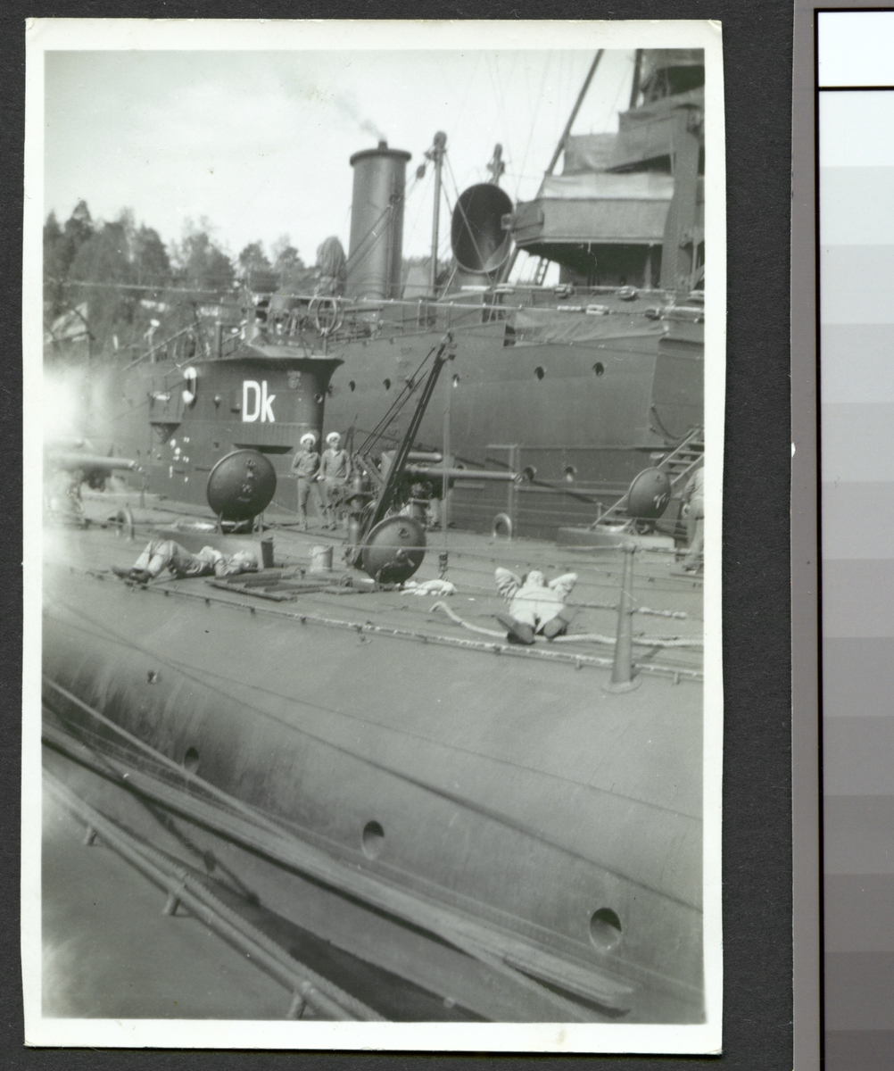 Bilden visar sjömän som tar en paus på däck av ett ubåt som ligger förtöjt med andra örlogsfartyg.
