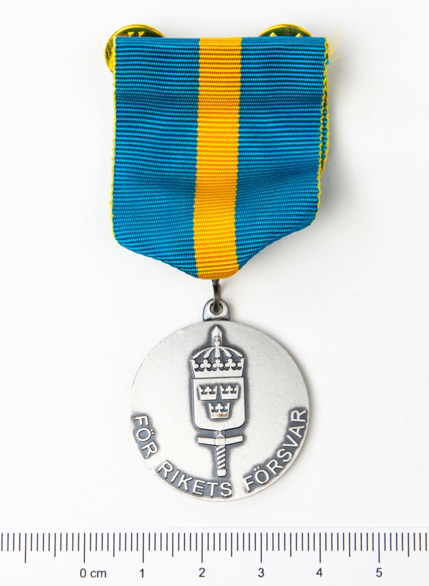 Framsidan har det svenska nationalitetsvapnet med tre kronor och ett svärd med texten "För rikets försvar". Baksidan har en lagerkrans samt texten F4 Gu 03/04.
Förvaras i originalask.
