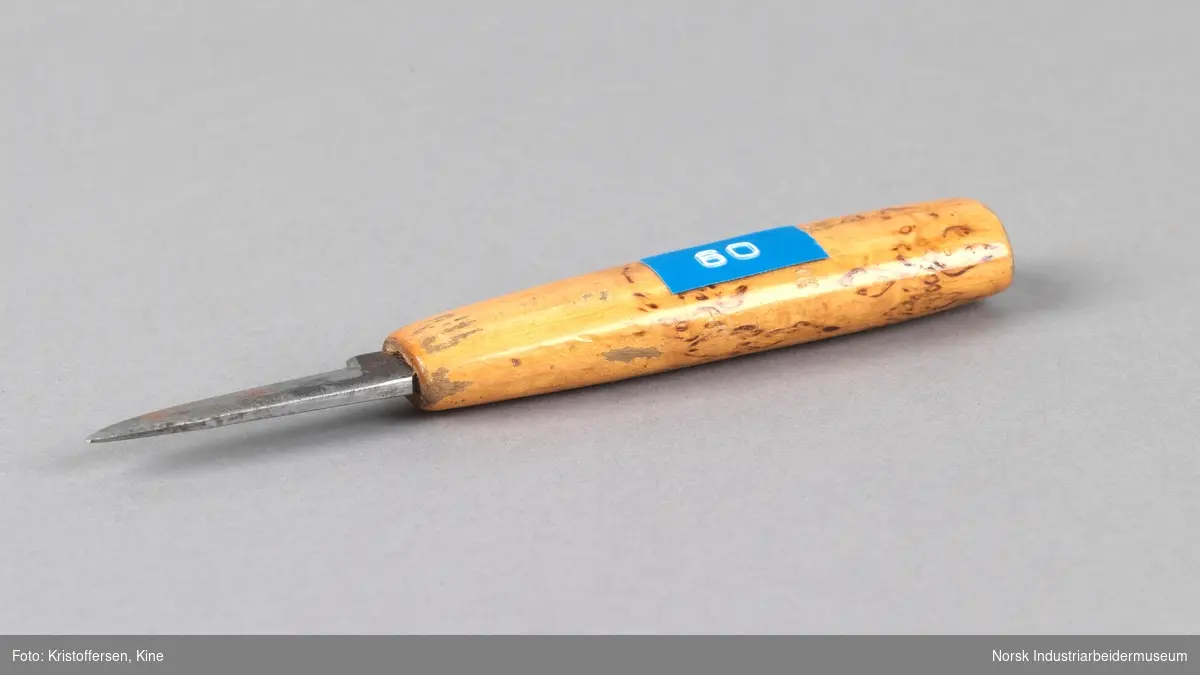 Kniv (blyantspisser), portvakt. Liten kniv med håndtak i tre. Knivbladet har fordypninger på den ene siden