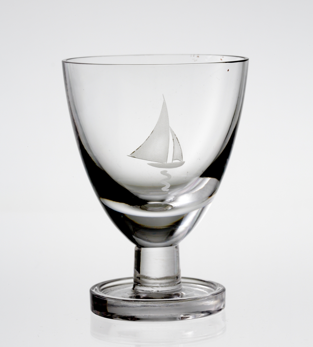 Design: Nils Landberg.
Portvinsglas. Tulpanformad kupa, med graverad segelbåt på kupan. Lågt, konande ben med vulstkantad fot.