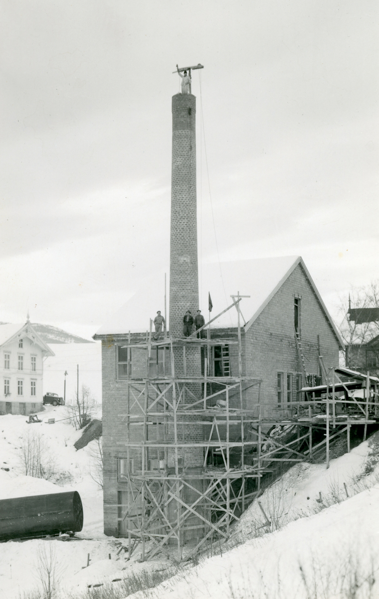 Foto av bygging av pipe ved Bø meieri.
Laga som prospektkort