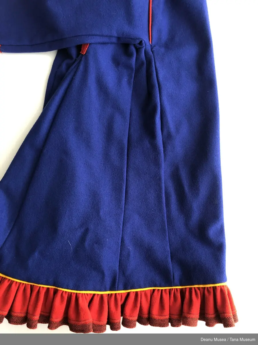 Blå jentekofte i ullklede fra Alleknjarg med røde pyntekanter. Rød holbi med gul pyntekant og rød/sort vevet bånd.