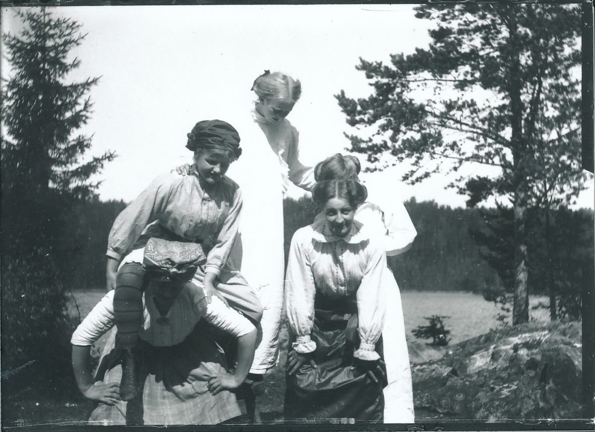 Medlemmer og/eller venner av Rydgrenfamilien morer seg på Mosjøhytta i Nordmarka. Fem jenter forsøker å lage slags turnformasjon. Innsjø og skog i bakgrunnen.