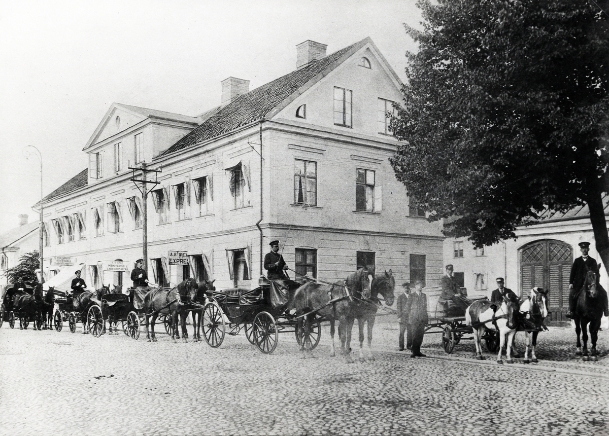 "Växjö Express", Storgatan 28 (kvarteret Tullen 5), Växjö, 1910. 
Personal och fordon i åkerifirman har ställt upp sig för fotografen.