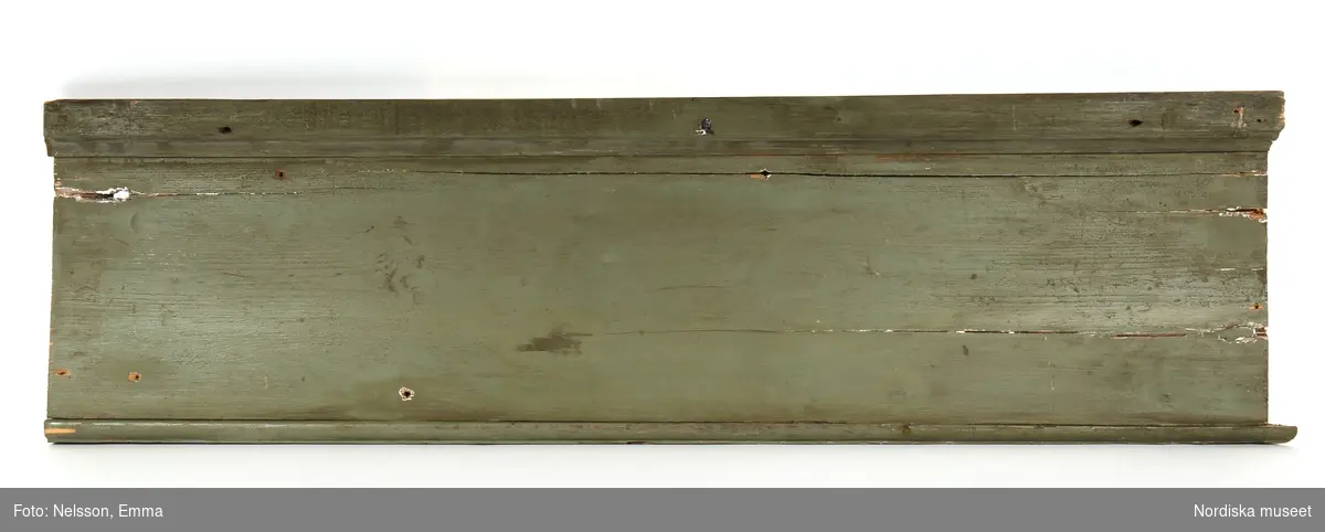 Fotsockel, 17 delar, varierande längder, av furu, målad i grågrön oljefärg, omkring 1740. Slät, med vulst upptill och profilering nedtill.

Anm: Partiellt färgbortfall och skador. En sockel har gått mitt itu, flera socklar kompletterade.
/Anna Arfvidsson Womack 2021-07-19
