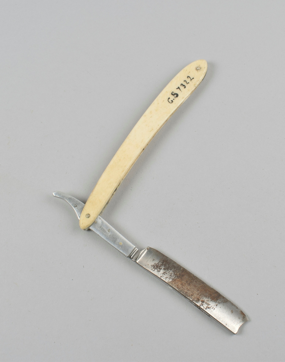 Sammenleggbar barberkniv med skaft i benmateriale, i futteral av papp kledd med tekstil.