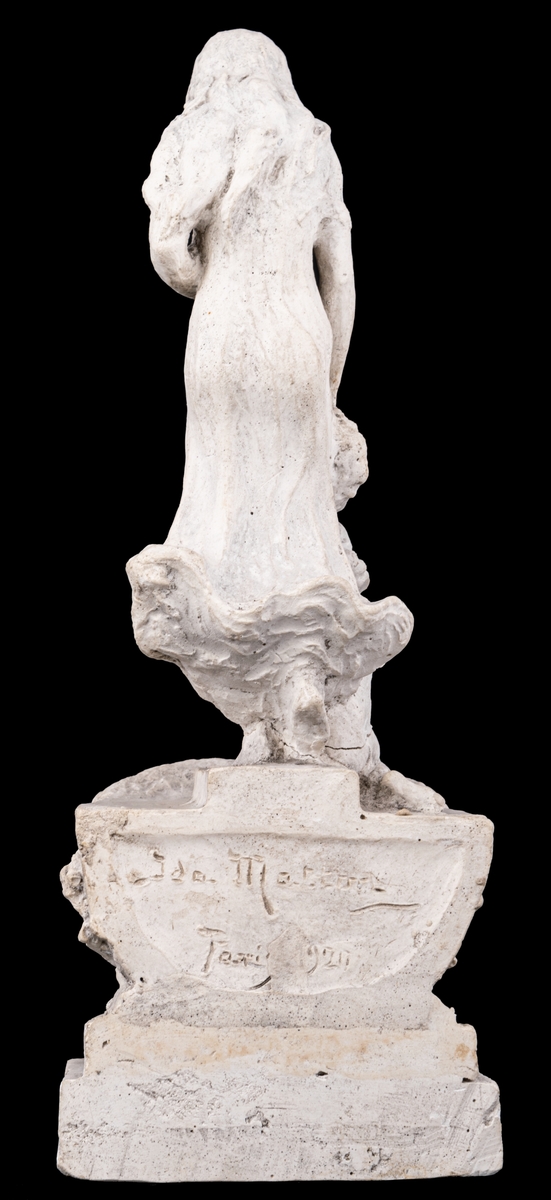 Skulpturskiss av Ida Matton, signerad Paris 1920, till gravmonument för redarfamiljen Brodin i Gävle. Kvinna med blommor i händerna med ett barn med blomgirlang sittande framför fötterna. Båda placerade på en trekantig sockel som liknar stäven på en båt.
