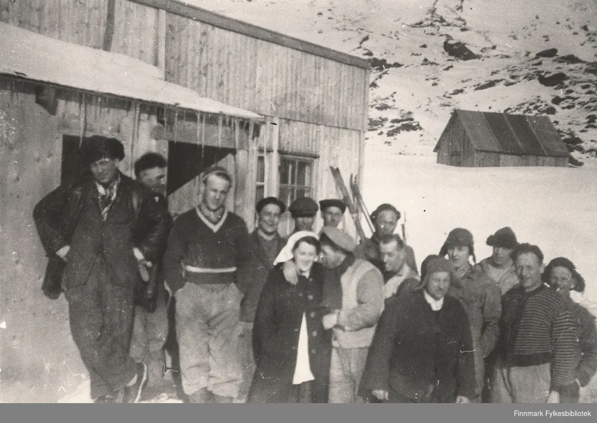 Her ser vi to arbeidslag utenfor brakka i Nordmanseth i Berlevåg i 1951. Vi ser et redskapshus i bakgrunnen.