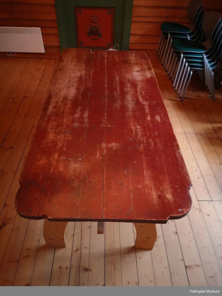 Bordplate i furu, malt rød med avkuttede, buede, profilerte hjørner.  Platen består av 3 bord som er holdt sammen ved hjelp av 2 labenker.