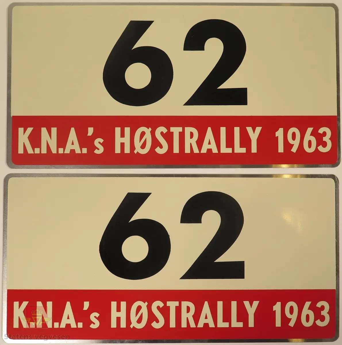 Hovedsakelig hvite metallskilt med et mindre rødt markeringsområde. Grupperingen med skilt har også nummeret "62" påført seg, dette er en indikasjon på deltakernummer.
Påskrift: K.N.A.'s HØSTRALLY 1963