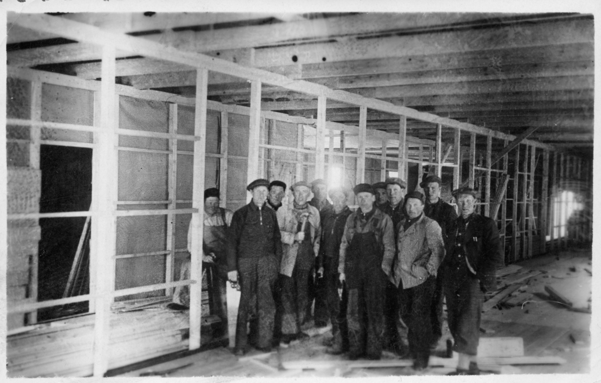 Gruppebilde av anleggsarbeidere, tatt inne på byggeplassen.