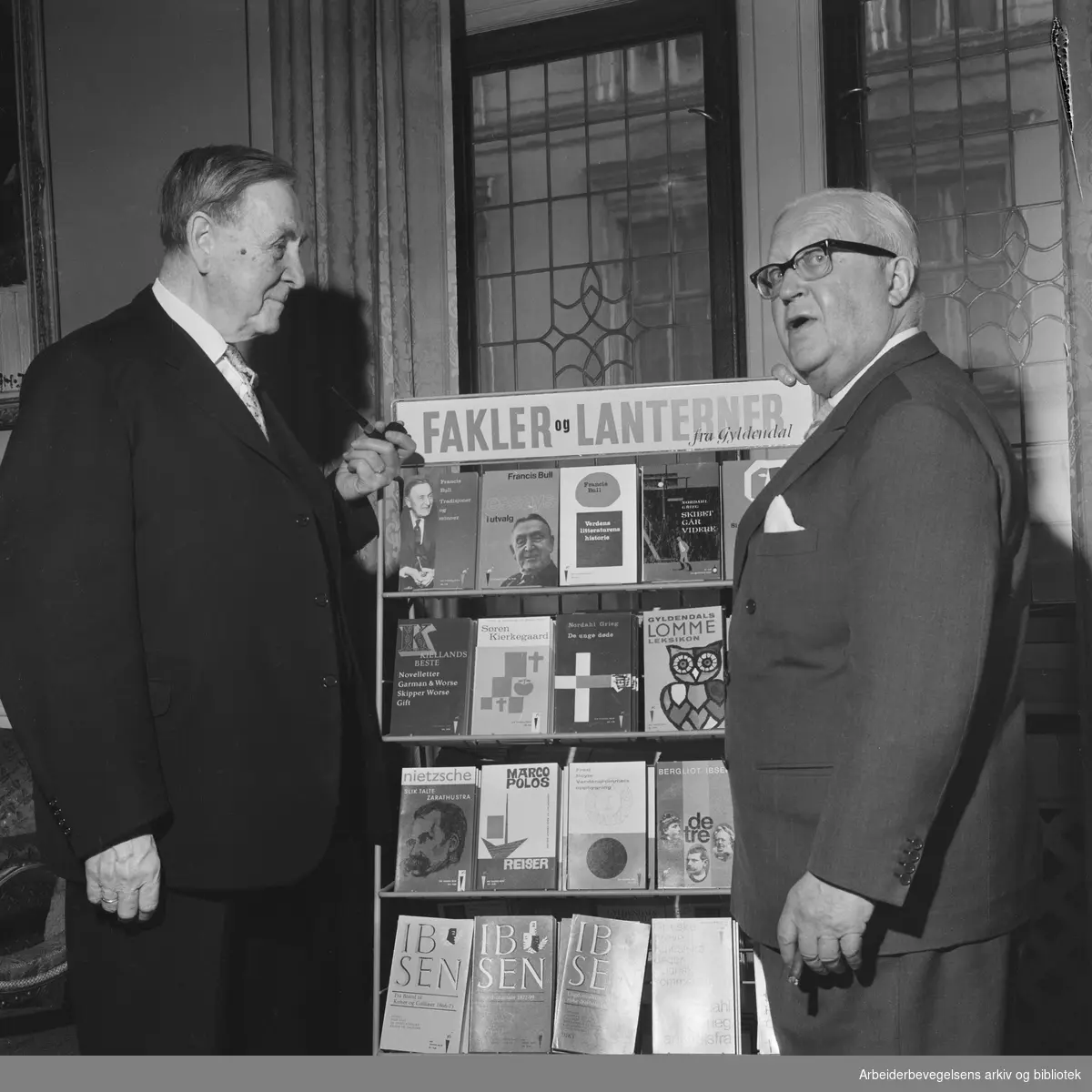 Litteraturprofessor Francis Bull (til venstre) og forlagsdirektør Harald Grieg lanserer nye utgivelser i Fakkel- og Lanterneserien under Gyldendals Norsk Forlags 40-års jubileumsmarkering i mars 1965