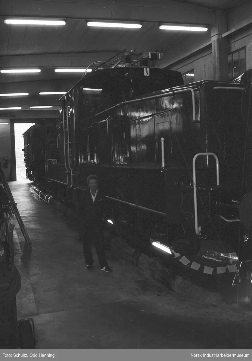 Mann ved Henschel diesel-lokomotiv, inne i lokomotivstallen.