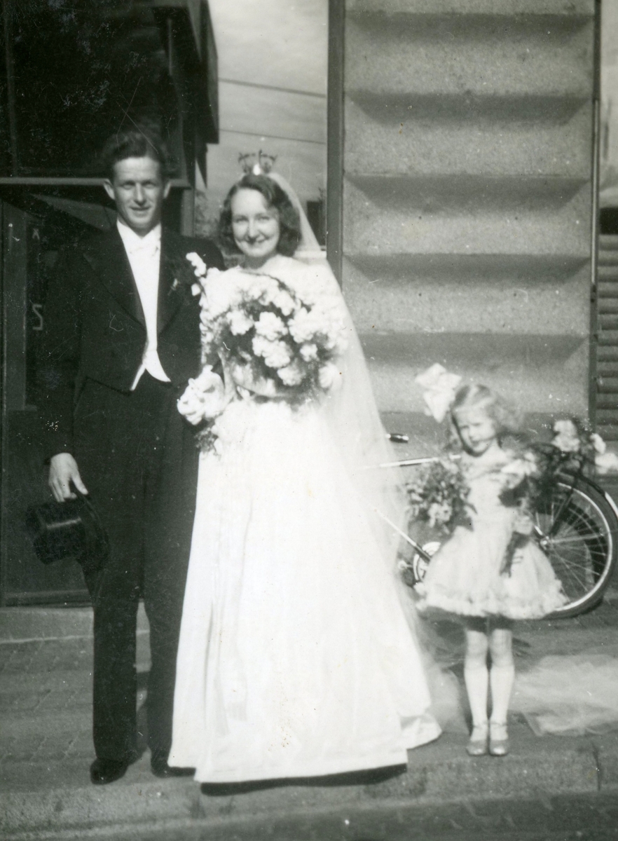 Bröllop mellan Mary Ekdahl (1920 - 1988, gift Ekman) och Björn Ekman (1913 - 1992), Hagakyrkan i Göteborg 1941-06-07. Paret står tillsammans med tärnan utanför kyrkan. Tärnan är okänd. Relaterat motiv: A2847.