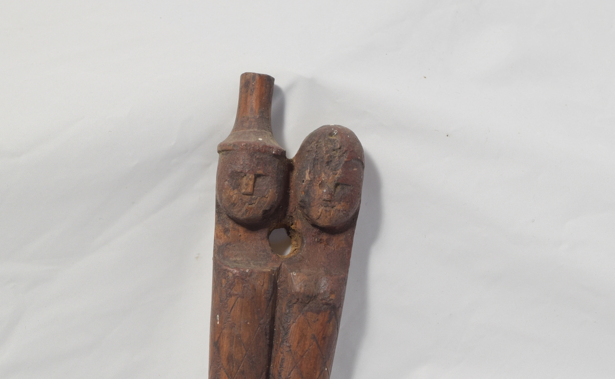 Kleskrok i tre med utskåret rutemønster. To hoder, en mann og en kvinne. Middelaldersk i formen.