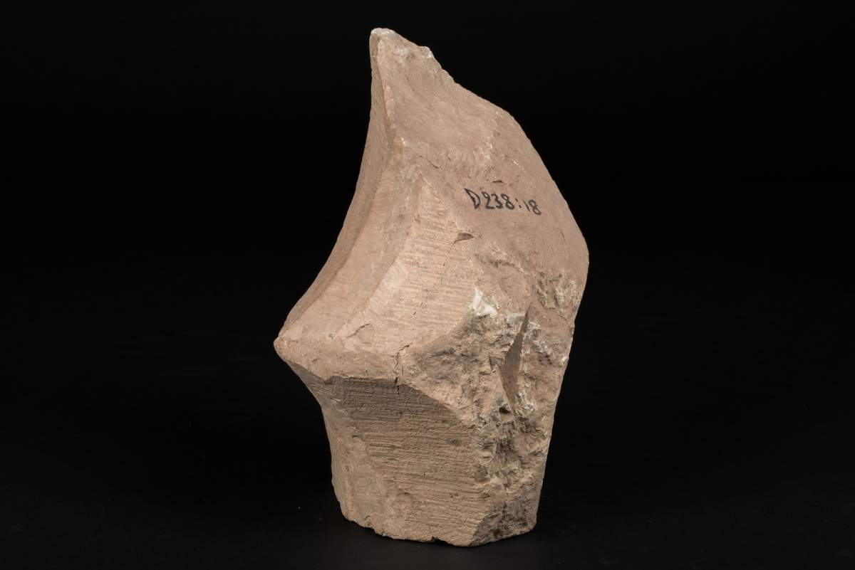 Del av masverk tillverkad av kalksten.
Stenen är huggen med tandjärn. Fragmentet saknar fals för fönsterbågar.