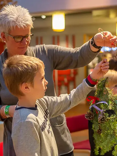 En voksen og et barn ser på julepynten de har laget på juleverksted på Anno Norsk skogmuseum