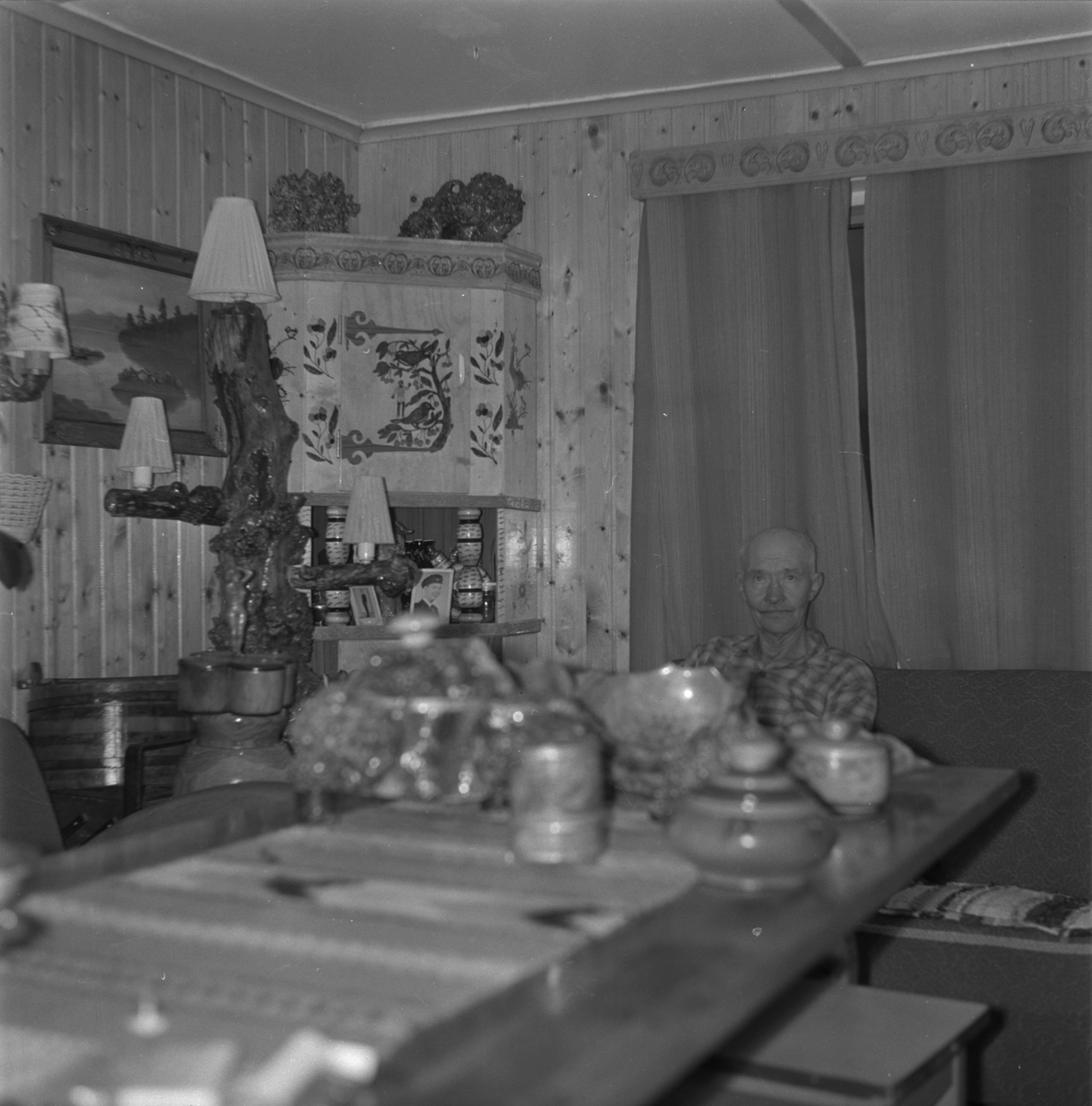 Ola Odland heime i stova på Meland i Etne, 1977. Rundt han er døme på trearbeidet hans.