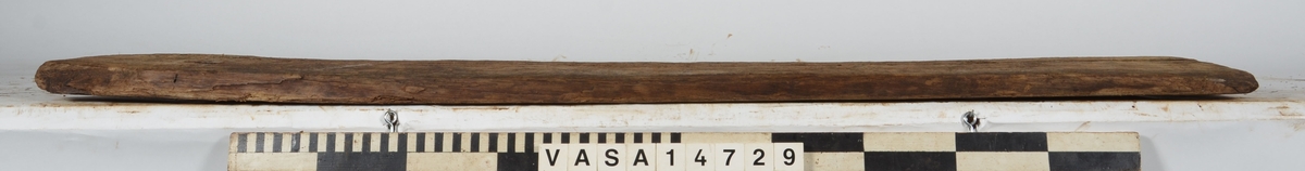 Planka tillhörande alpumpkistan i hålskeppet. Ena kanten skadad. Sågmärken finns på föremålet.