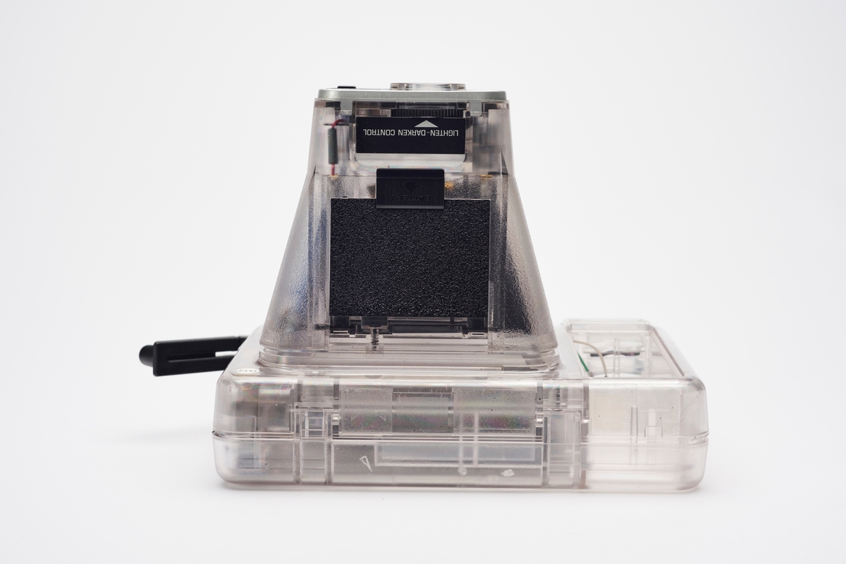 Kodak EK2 Instant Camera, også kalt The Handle, i gjennomsiktig plast. Kameraet er utstyrt med bl.a. autofokus, manuell bildeutløser, mulighet for avtagbar blits og anvendte Kodaks egen PR10 instant film. Kameraet er produsert av Kodak og er en av få som har fått beholde sitt originale navnemerke, da dette kamera mest sannsynlig aldri ble solgt, men har fungert som et visningseksemplar i butikk.  
Polaroid fikk på alvor en konkurrent på markedet da Kodak begynte å produsere instant kameraer og film i 1976. På 1960-tallet hadde Kodak produsert film for Polaroid, men nå var stemningen en annen. Dette var ikke et samarbeid og Polaroid, som hadde patent på produktet, svarte med å gå til rettssak. Det var en langvarig rettssak. Kodak ble nødt til å trekke sine instant-produkter fra markedet i 1986. I 1990 var erstatningssummen avklart og året etter måtte Kodak betale Polaroid 925 millioner amerikanske dollar (inkludert renter). Dette var den største erstatningssummen noen gang frem til 2012. I tillegg måtte Kodak kompensere sine kunder som hadde kjøpt instant kameraer av dem fra 1976 til 1986, da de nå ikke lenger fikk kjøpt film som passet. Kunden ble bedt om å ringe et gratisnummer og registrere seg for å få tilsendt en pakke i posten, som inneholdt instrukser for hvordan de kunne få kompensasjon. Ofte involverte dette at de måtte ta av kameraets navnemerke og sende tilbake som et bevis for at de eide kameraet. I dag er instant kameraer fra Kodak uten navnemerket mer vanlig enn med.