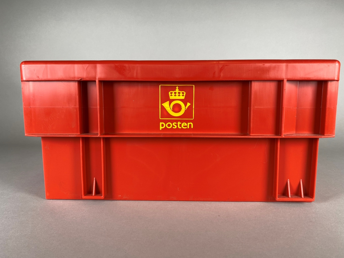 Rød kasse med postens logomerke på begge langsider. Utformet i legoklossprinsipp ved at den kan stables sammen med lignende kasser. Håndtakene har forskjellige farge, gul og svart. Postkassetten har også en påklistret strekkode.