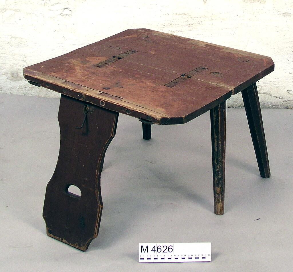 Bordstol, av barrträ. Målad i rödbrunt. Fyra åttkantiga ben. Ryggbrädan profilerad och med halvmånformigt hål. 