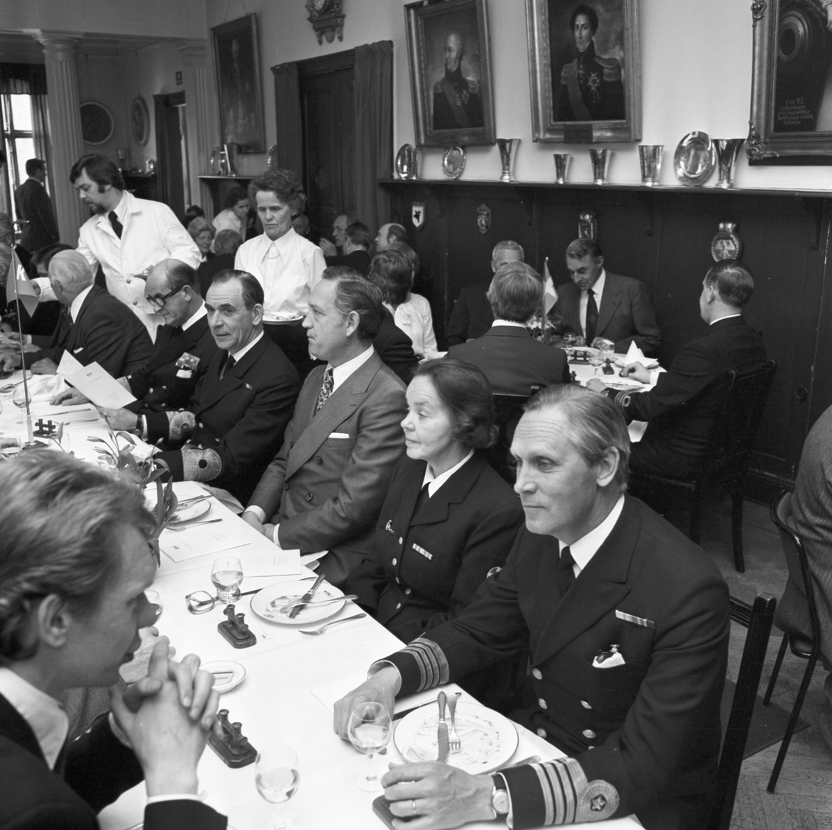 Bilden visar personal från Marinen och Karlskronavarvet på en middag efter torpedbåten Stömstads T-141 sjösättning.
Mannen till höger är chefen för Sydkustens örlogsbas, kommendör av 1. graden Lennart Ahrén. Längre till vänster i samma rad syns  chefen för försvarets materielverks huvudavdelning för marinmateriel, konteramiral Gunnar Grandin och marinchefen, viceamiral Bengt Lundvall.