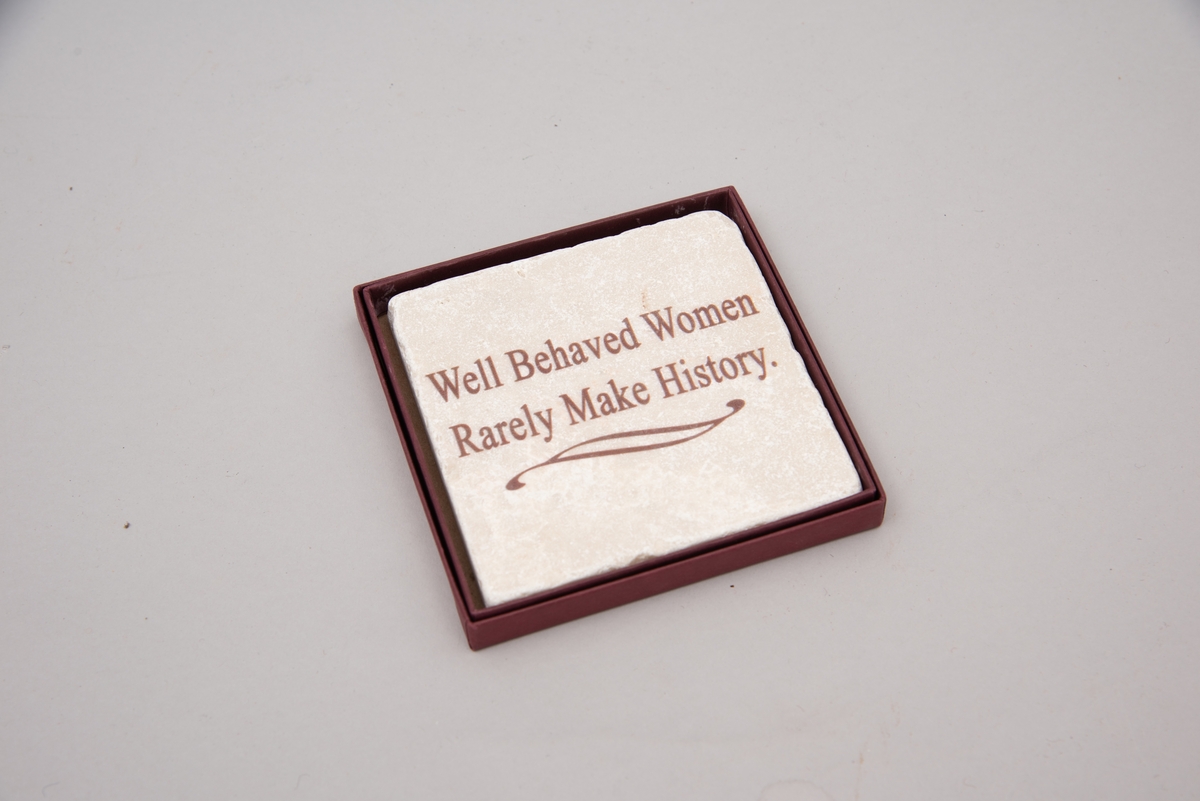 Marmorflis og souvenir fra Newsport Mansions med påført slagord "Well Behaved Women Rarely Make History". Tilhørende eske og informasjonsfolder. Mottoet påført marmorflisa er i ettertida blitt brukt til å beskrive Alva Vanderbilt Belmont (1853-1933) og andre kvinner som kjempet for kvinners stemmerett på begynnelsen av 1900-tallet i USA under slagordet "Votes for Women". Selve "Votes for Women"-mottoet ble brukt i 1909 på et berømt "open house" stemmerettsmøte holdt på Marble House, Newport, Rhode Island".