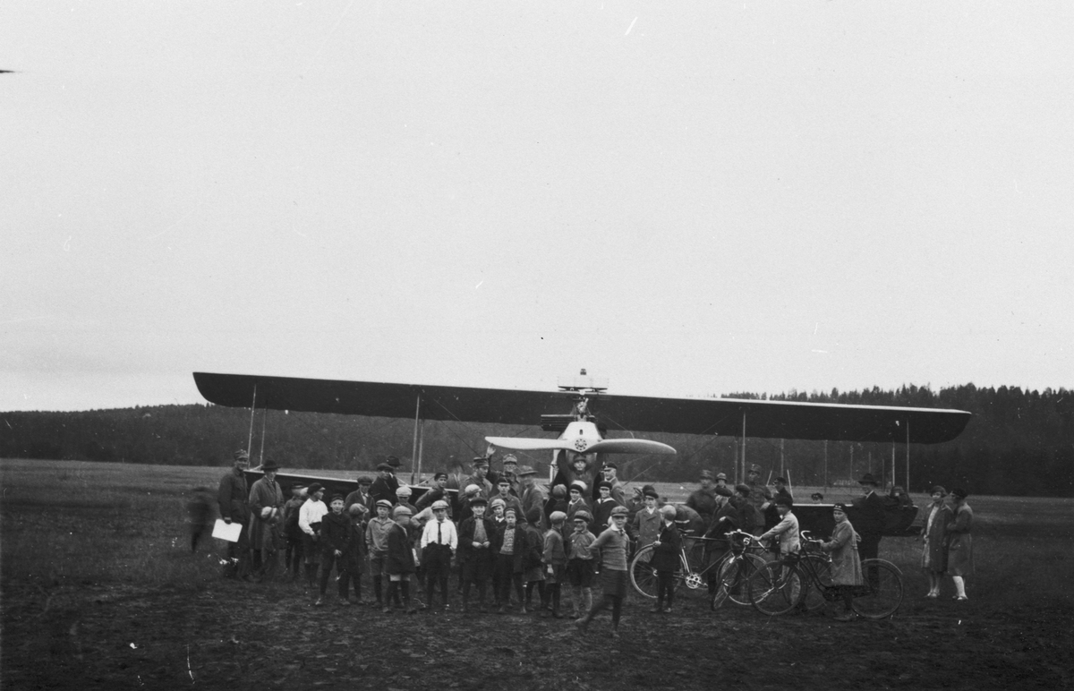 Folksamling framför flygplan FVM Albatros 160 på ett flygfält, 1910-1925. Militärer, civila män och barn.