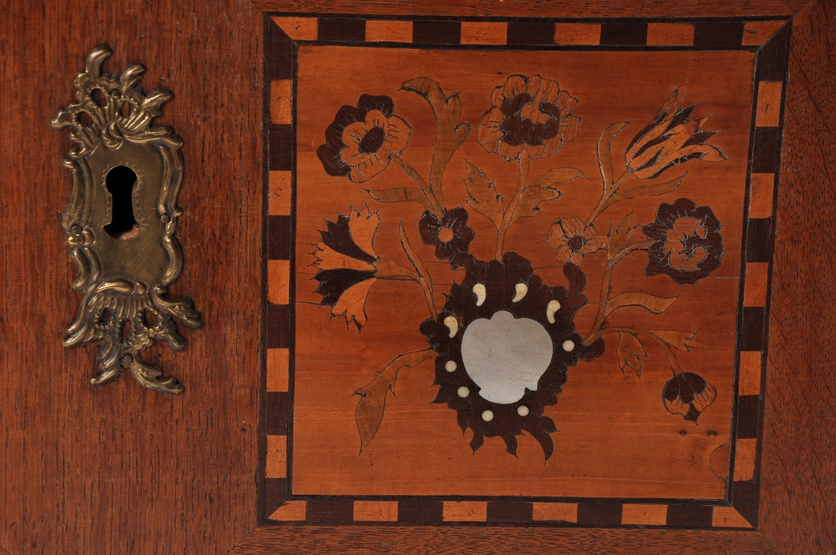 Fredrikshalds liklaugs kiste i tre, med intarsia dekorasjoner. På forsiden innsatt med perlemor med inskripsjon. På lokket en dødningsskalle i ben. Med  håndtak i messing.