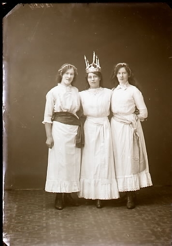 Ateljébild av Lucia med två tärnor stående i helbild. Kvinnan till höger heter Sigrid Collin. Fotografen har noterat: Trafikchef Collin. Beställare: Ida Johansson. (Se även bild GB2_5557)