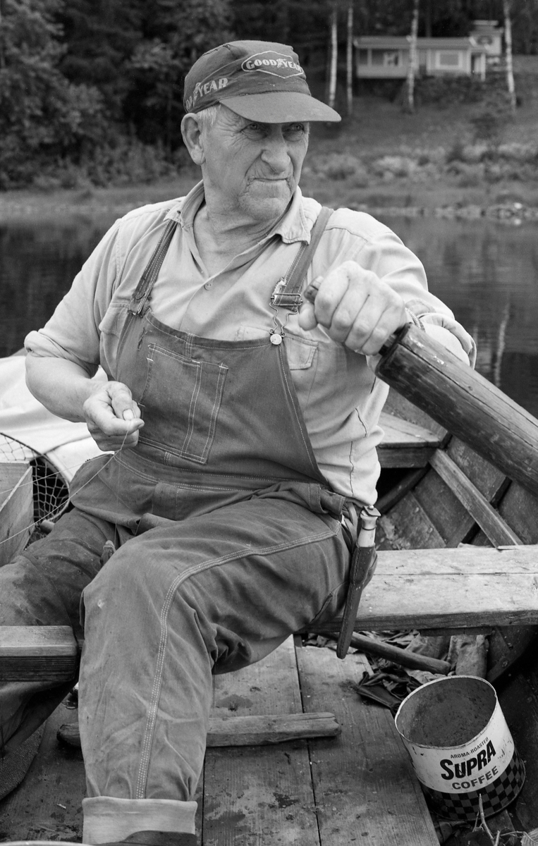 Yrkesfiskeren Paul Stensæter (1900-1982), fotografert i båten sin på Steinsfjorden, en sidearm til Tyrifjorden på Ringerike (Hole kommune) i Buskerud. Stensæter har fanget ørekyte (Phoxinus phoxinus) eller «kime», en liten karpefisk som ble brukt som agn under abborfiske med reiv. Reiven var ei lang line som det var fastknyttet fortommer med kroker på. Det var disse krokene som ble egnet med kime. Reivfisket etter abbor var en sommeraktivitet. Fiskeren var kledd i dongerioverall og ei ensfarget flanellskjorte. På hodet hadde han ei skyggelue, et reklameprodukt fra bildekkprodusenten Goodyear.

I 1970-åra var etnologen Åsmund Eknæs fra Norsk Skogbruksmuseum flere ganger på besøk hos Paul Stensæter for å observere ham i arbeid og intervjue ham om fiskeaktivitetene på ulike tider av året. Museumsmannen sammenfattet den kunnskapen han tilegnet seg om reivfisket og bruken av «kime» som agn i Steinsfjorden slik:

«Det kanskje mest effektive redskap på abboren var reiven. Når to stykker fisket sammen var det mulig å ha abborreiv med opptil 1 000 kroker. Disse hang i ca. 30 cm lange tamser med 2 favners mellomrom. Vi fikk altså her ei line på omkring 4 kilometers lengde! Reiven ble ikke satt på samme sted to dager i trekk. De satte den «bassenget rundt», dvs. at de fulgte en bestemt rutine for å få fisket rundt hele fjorden.

Da Paul gikk over til å fiske aleine nøyde han seg med 600 kroker. Agn var, så lenge det var lovlig, levende ørekyte, «kimer», Kima hadde han gående i en vannstamp med et klede over. Kledet hang litt ned i vannet slik at det ble en liten dam på oversida. Oppi her tok han en neve kime etter hvert som han trengte det. Reiven ble oppbevart i ei kasse med slinner langs kantene til feste for krokene. Paul greide å egne og kaste uti ca. 100 kroker på et kvarter. Da måtte han også få båten framover etter hvert som reiven ble satt ut.»